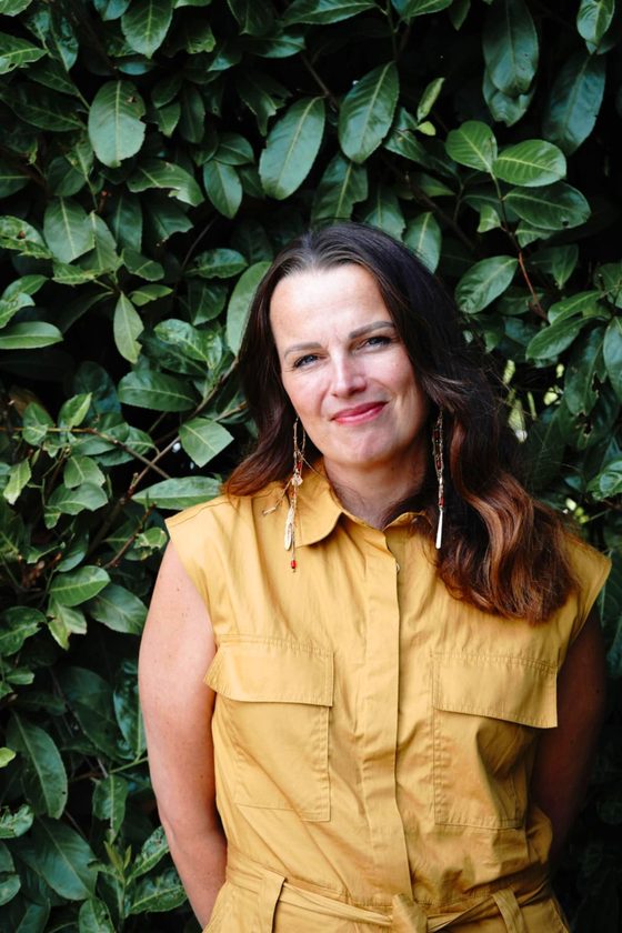 Portrait of Jennifer, founder of First Oak Therapy, smiling in front of green foliage